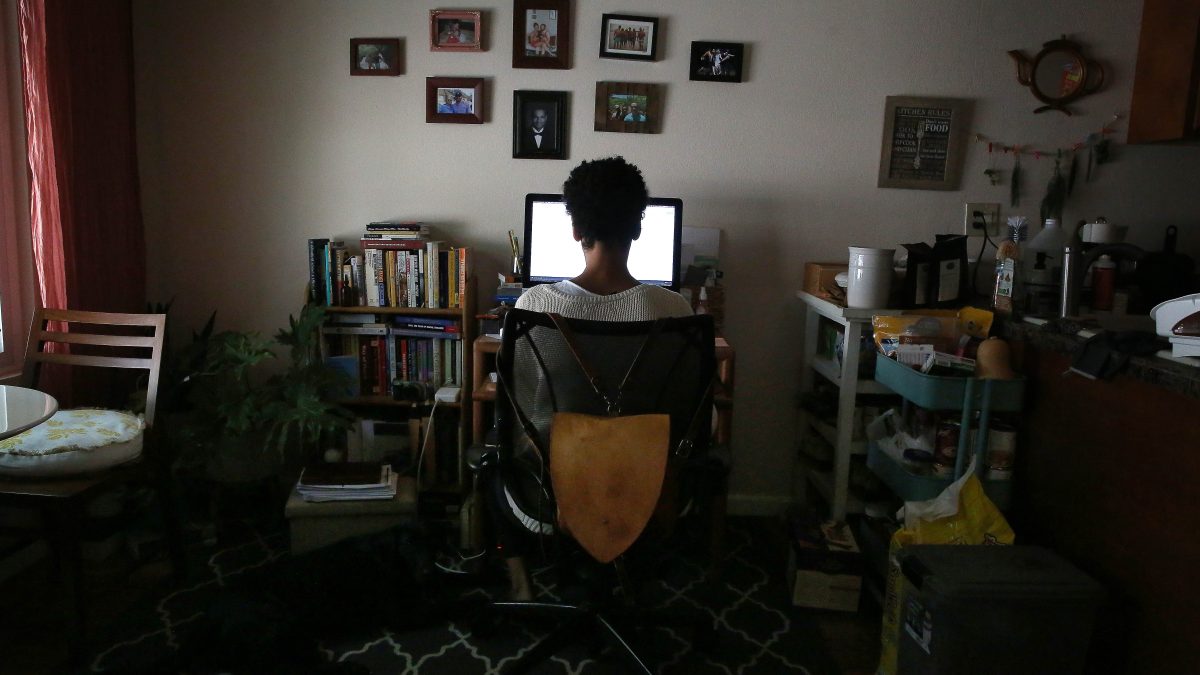 Lucia Momoh, UC Berkeley Art Museum & Pacific Film Archive (BAMPFA) curatorial assistant, works on her computer at her home office underneath a display of photos of famiy and loved ones on her wall on Wednesday, August 12, 2020 in Rohnert Park, Calif.  Mo