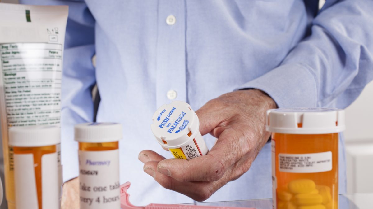 Senior adult man gets prescription medicines out of cabinet.