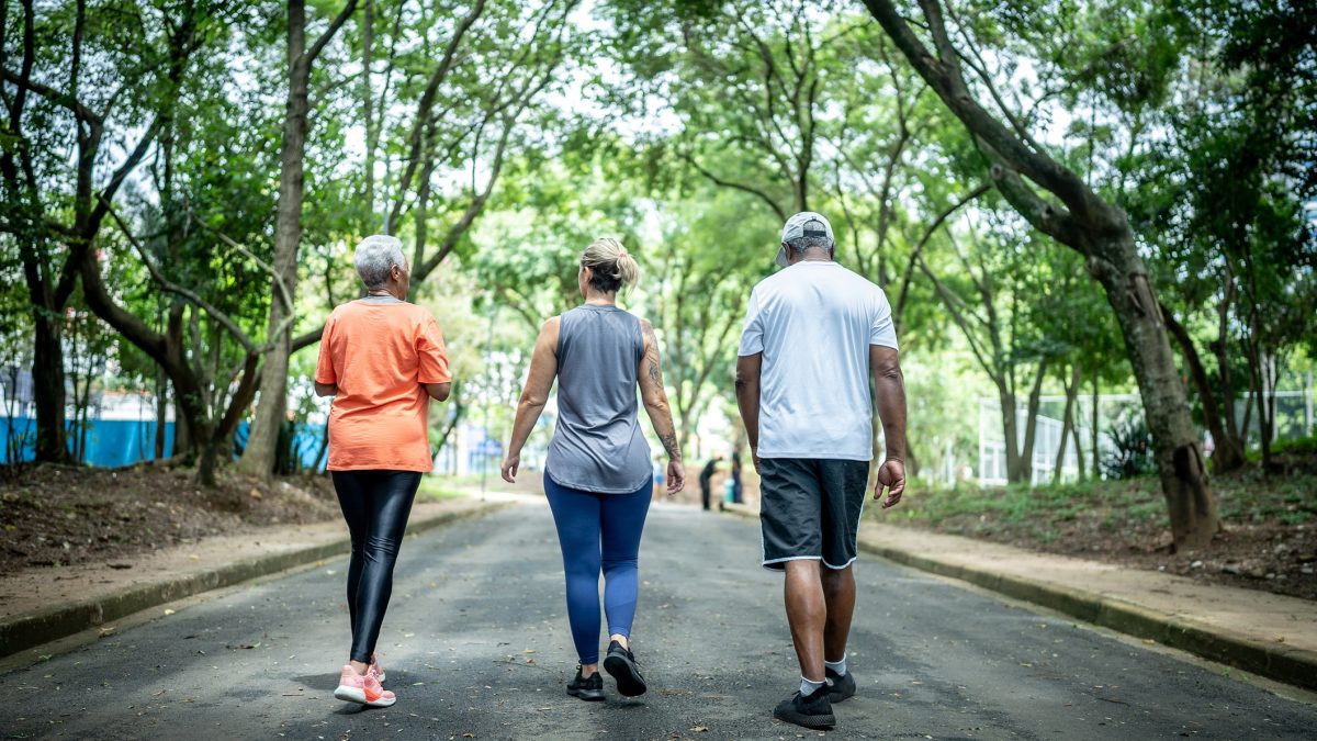 Fitness instructor walking with senior couple at public park
